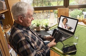 Symbolic image of telemedicine, elderly patient speaks to a doctor in a video conference from home,