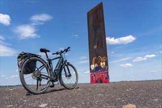 Cycling in the Ruhr area, on the Schurenbach slag heap, Bramme landmark for the Ruhr area by artist