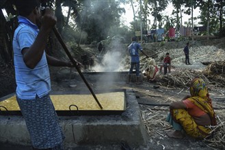 Workers boiling sugarcane juice as they are making Gur (jaggery) in a village on December 10, 2021