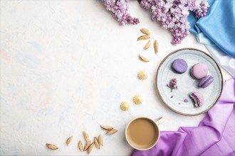 Purple macarons or macaroons cakes with cup of coffee on a white concrete background and