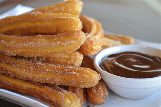 Close up of Churros with chocolate sauce on plate. A fried dough dessert from Spanish and