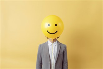 Person in business suit with yellow balloon with smiling face, AI generated