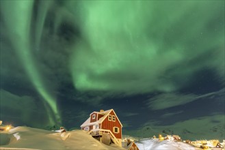 Northern Lights, Aurora borealis over red house, Inuit settlement, Winter, Tasiilaq, East