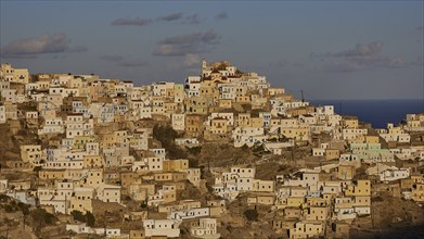 An ensemble of buildings on a hillside with a sea view, atmospherically captured in the golden