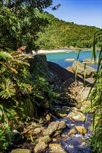 Indaiauba beach on Ilhabela island with the river flowing through the vegetation