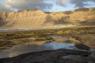 Late afternoon light on beach and cliffs La Caleta de Famara, Lanzarote, Canary islands, Spain,