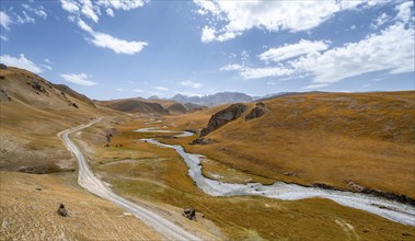 River Kol Suu winds through a mountain valley with hills of yellow grass, Naryn Province,