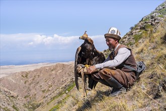 Traditional Kyrgyz eagle hunter with eagle in the mountains, near Kysyl-Suu, Kyrgyzstan, Asia