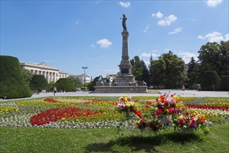 A sunny park with a large monument surrounded by colourful flowerbeds and green trees, Municipal