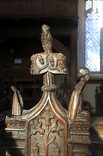 Ornately decorated wooden pew end of woman praying, Ufford church, Suffolk, England, UK