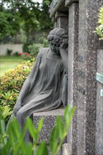 Figure in a cemetery, family grave, old gravestone, with flower and grave light, North