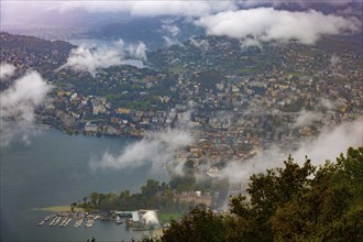 Aerial View over City and Lake Lugano in Valley with Mountainscape with Storm Clouds in Lugano,