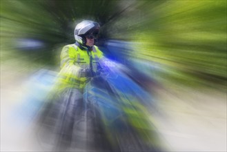 Policeman on a motorbike driving fast along the road, the speed is emphasised by the motion blur,