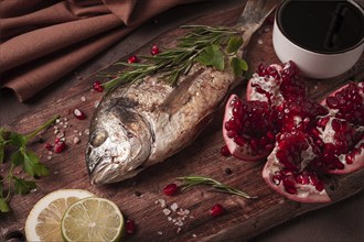 Fried dorado fish, with spices and herbs, on a wooden board, pomegranate sauce, close-up, no people