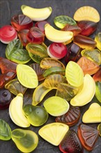 Various fruit jelly candies on black concrete background. side view, close up