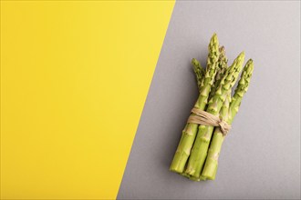 Bunch of fresh green asparagus on gray and yellow pastel background. Top view, flat lay, copy space