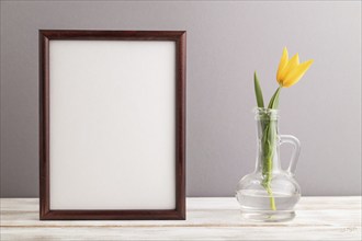 Wooden frame with orange tulip flower in glass on gray pastel background. side view, copy space,