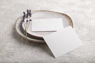 White paper invitation card, mockup with lavender on ceramic plate and gray concrete background.