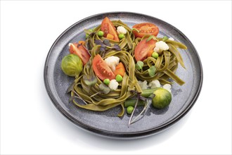 Tagliatelle green spinach pasta with tomato, pea and microgreen sprouts isolated on white