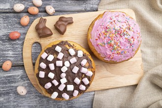 Homemade glazed and decorated easter pies with chocolate eggs and rabbits on a gray wooden