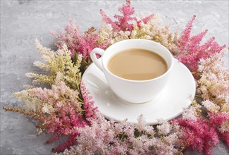 Pink and red astilbe flowers and a cup of coffee on a gray concrete background. Morninig, spring,