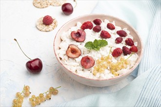 Rice flakes porridge with milk and strawberry in ceramic bowl on white concrete background and blue