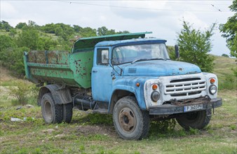 Weathered blue lorry on a rural meadow under a cloudy sky, ZIL-130, Soviet Russian vehicle