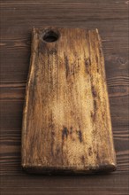 Empty rectangular wooden cutting board on brown wooden background. Side view, close up