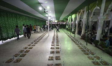 Volunteers distribute and arrange rows of 'iftar' meal for devotees to break their fast, during the