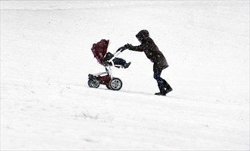 A woman pushes a pram through a snow-covered park in the freezing cold, Berlin, 09/02/2021