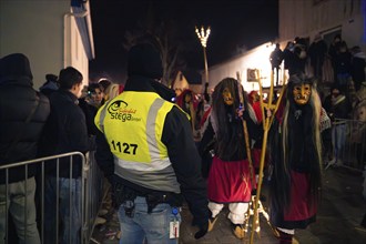 Security employee observes group of masked persons at a night event, carnival, Schellbronn night