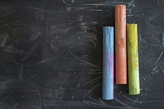 Top view of colorful chalk pieces on black chalkboard. KI generiert, generiert, AI generated