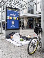 Homeless man sleeping in front of the entrance to Dortmund Central Station, North Rhine-Westphalia,