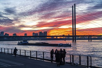 Winter sunset on the Rhine near Düsseldorf, riverside promenade at the old town, cargo ship,