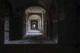 A dark, deserted corridor with vaulted ceilings leads into a mysterious depth, Beelitzheilstätten,