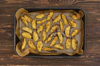 Top view of potato wedges baked in oven in baking tray