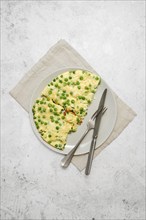 Omelet with fresh green peas and cheese on a plate on a grey stone tabletop