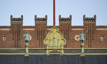 Brick façade with gilded city coat of arms, town hall in the National Romantic style by Martin