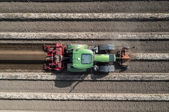 A farmer builds asparagus ridges on a field with the help of an asparagus tiller, in which the