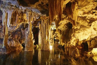 Cave with illuminated stalactites and stalagmites, reflection in the water, stalactite cave, Diros