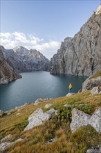 Tourist at the blue mountain lake between rocky steep mountain peaks, Kol Suu Lake, Sary Beles