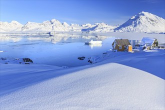 Inuit settlement, houses in front of icebergs in icy fjord, mountains, winter, snow, sunny,