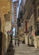 Steps climb hill of narrow street historic housing with traditional balconies in city centre of