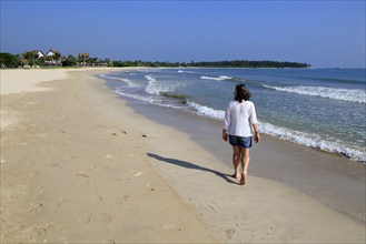 Ocean and woman walking on sandy tropical beach at Pasikudah Bay, Eastern Province, Sri Lanka, Asia