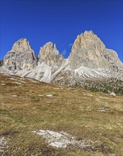 Wide meadow landscape in front of an impressive mountain backdrop on the Sella Pass under a clear