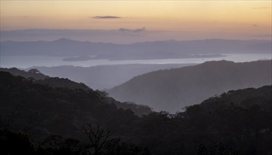 View to the sea over wooded hills, at sunset, cloud forest, Monte Verde, Puntarenas province, Costa