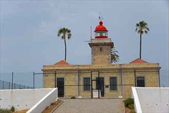 A traditional lighthouse with red roofs and palm trees, surrounded by a coastal landscape, Ponta da