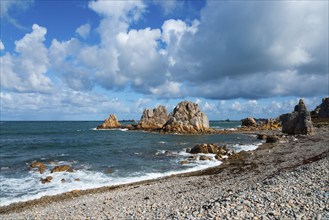 Rocks and sea on a coastline under a dramatic sky with clouds and blue sky, Plage de Pors Scaff,