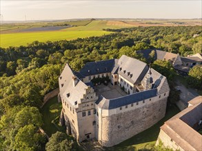 Aerial view of a medieval castle surrounded by green trees and fields, Harz Mountains, Allstedt,