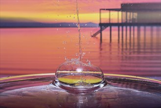 Splash of a drop falling into water, studio shot with Lake Constance motif as background, Bavaria,